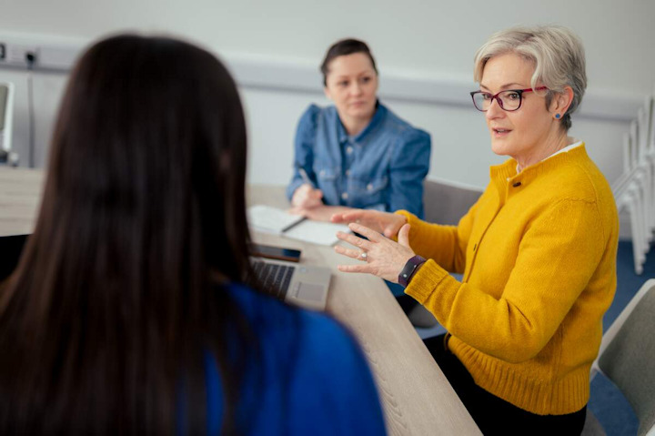 Students and tutor sit around a table for a seminar discussion